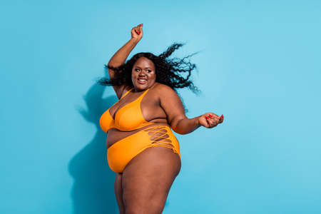 Profile side view portrait of attractive cheerful thick woman dancing having fun isolated over bright blue color backgroundの写真素材
