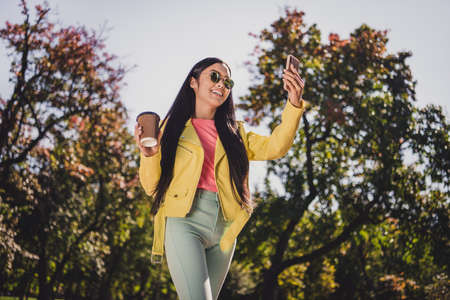 Photo of attractive carefree cool lady hold paper takeaway cup make selfie enjoy sun rays free time...