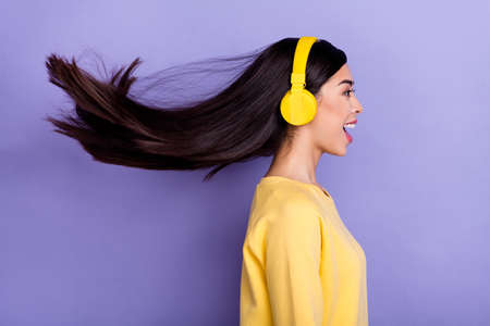 Profile side photo of young excited girl look empty space listen radio earphones mp3 isolated over purple color backgroundの写真素材