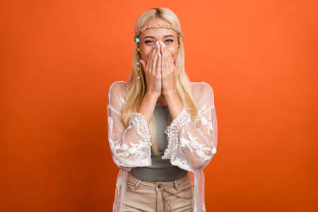 Portrait of attractive cheerful girl laughing closing face isolated over bright orange color backgroundの写真素材