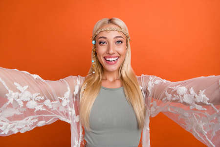 Self-portrait of attractive cheerful blond girl having fun travel trip good look isolated over bright orange color backgroundの写真素材