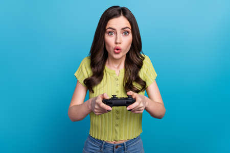 Photo of impressed millennial brunette lady playstation wear green t-shirt isolated on blue...