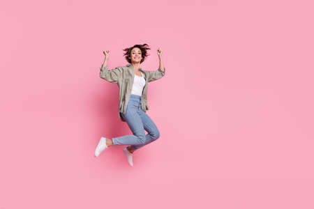 Full length photo of young woman jump rejoice success lucky fists hands triumph isolated over pink...