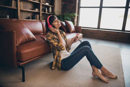 Full length photo of funny millennial bob hairdo lady listen music hold telephone wear shirt jeans bare foot at home modern flat aloneの写真素材