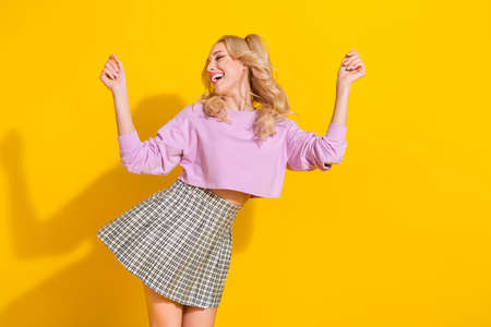 Photo of overjoyed satisfied girl clubbing spend free time isolated on yellow color background