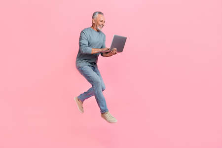 Photo of charming retired man wear grey shirt jumping chatting gadget empty space isolated pink...
