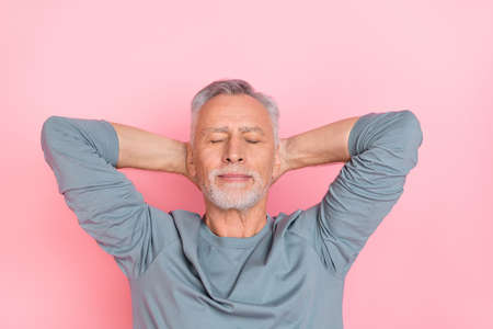 Photo of funny dreamy retired man wear grey shirt arms behind head closed eyes isolated pink color backgroundの写真素材
