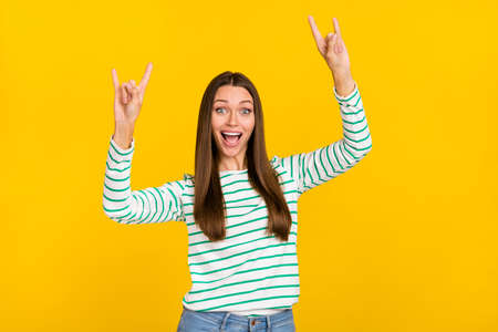 Photo of young cheerful girl show fingers rock symbol brutal careless isolated over yellow color...