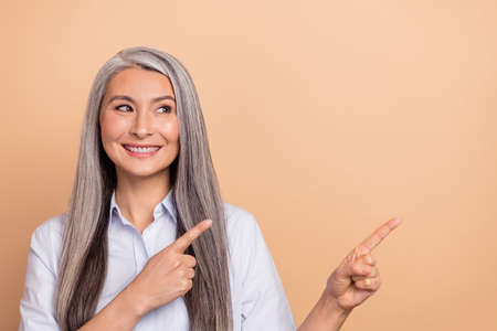 Photo of aged woman look indicate fingers empty space proposition discount isolated over beige color...