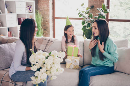 Portrait of adorable careful attractive cheerful family giving roses to mommy congrats 8 March at...