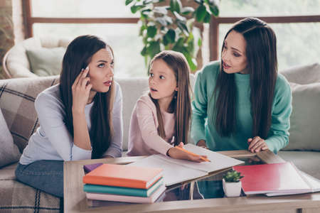 Photo of mommy with siblings sitting divan apartment help with lesson homework minded thoughtful...