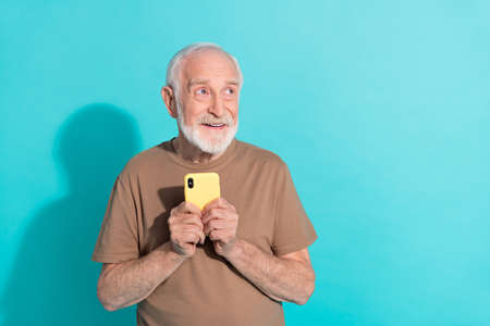 Portrait of attractive trendy cheerful grey-haired man using gadget thinking copy space isolated...