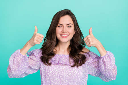 Portrait of attractive cheerful girl showing thumbup ad nice agree isolated over bright blue color backgroundの写真素材