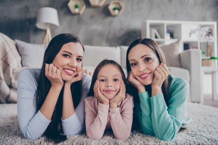 Portrait of attractive careful sweet cheerful family lying on floor enjoying comfy atmosphere growth...