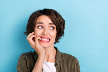 Photo of impressed young brunette lady bite fingers look wear shirt isolated on blue color backgroundの写真素材