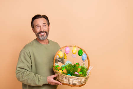 Portrait of attractive minded cheerful man holding in hands festal basket creating solution isolated...