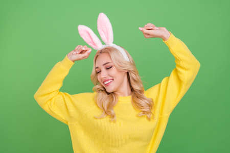 Photo of pretty young blond lady dance wear ears yellow pullover isolated on green color backgroundの写真素材
