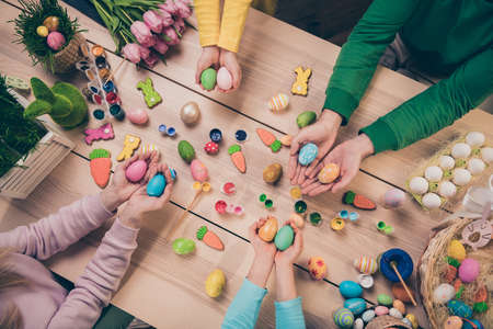 Above view cropped portrait of four people arms palms hold painted handmade eggs event occasion indoorsの写真素材