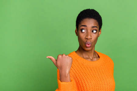 Photo of impressed young short hairdo lady look promo wear orange sweater isolated on green color...