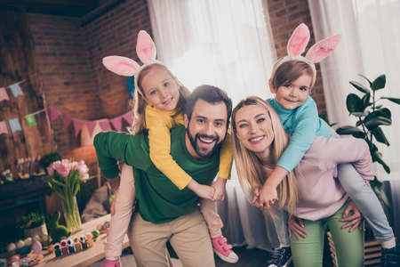 Portrait of four positive overjoyed idyllic people have fun hold piggyback kids house indoorsの写真素材