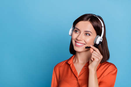 Profile side photo of young cheerful girl listen agent earphones look empty space isolated over blue color backgroundの写真素材