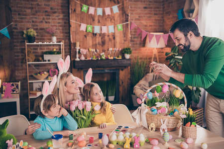 Photo of good mood family spend holiday weekend indoors daddy take picture of his family give mom flowers prepare easter holiday partyの写真素材
