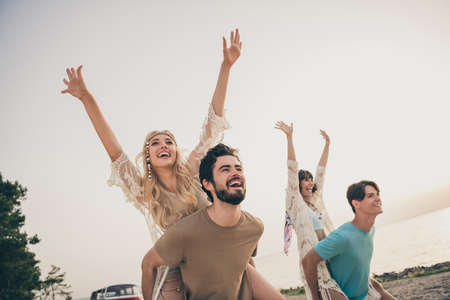 Photo of millennial funky two girlfriend boyfriend piggyback go on exotic holiday trip wear hippie cloth outdoorsの写真素材