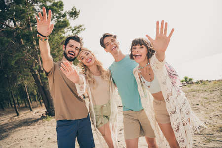 Photo of four friendly buddies make remote zoom video call wave hand wear casual outfit nature...