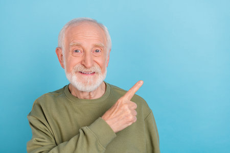 Portrait of attractive cheerful grey-haired man demonstrating copy blank space ad isolated over...