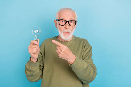 Portrait of handsome trendy stunned grey-haired man showing bulb wow look isolated over bright blue color backgroundの写真素材