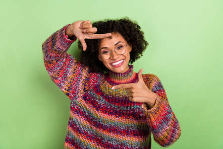 Photo of nice millennial curly lady take photo wear red turtleneck isolated on green color backgroundの写真素材