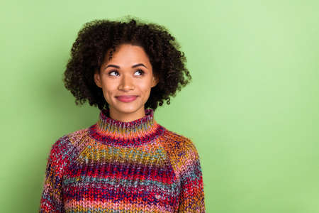 Photo of minded adorable girl look interested empty space imagine isolated on green color backgroundの写真素材