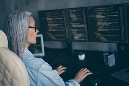 Profile side view portrait of attractive focused skilled grey-haired woman writing code solving at...