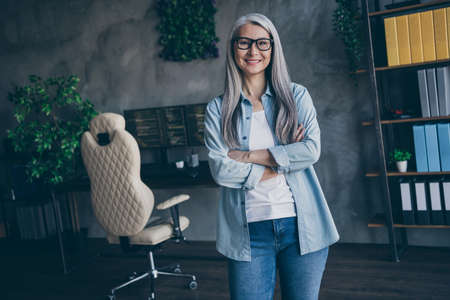 Photo of cheerful pretty aged lady web designer folded arms toothy smile look camera loft room indoorsの写真素材