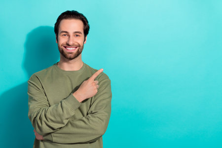 Photo of nice brunet young guy index promo wear green shirt isolated on teal color backgroundの写真素材