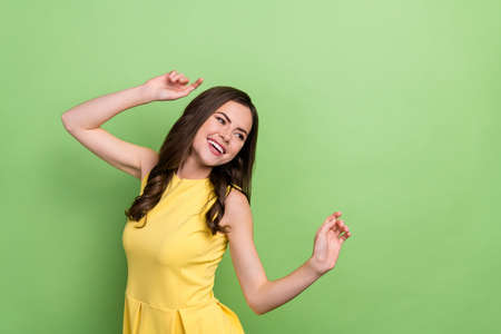 Portrait of attractive cheerful girly wavy-haired girl dancing enjoying festal occasion isolated over bright green color backgroundの写真素材