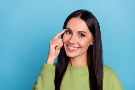 Photo of positive charming young girl touching forehead ask you to remember think isolated on blue color backgroundの写真素材