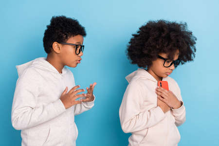 Portrait of small little pre-teen friends friendship using device gadget hiding play game app isolated over bright blue color backgroundの写真素材