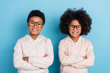 Portrait of attractive cheerful brunet kids nerds schoolkids folded arms isolated over bright blue color backgroundの写真素材