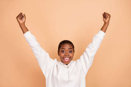 Photo of celebrate millennial brunette lady hands fists wear white hoodie isolated on beige color backgroundの写真素材