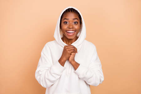 Portrait of pretty cheerful person hands hold hood head beaming smile isolate don beige color backgroundの写真素材