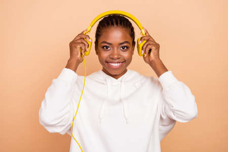 Photo of optimistic young brunette lady wear headphones sportscloth isolated on beige color backgroundの写真素材