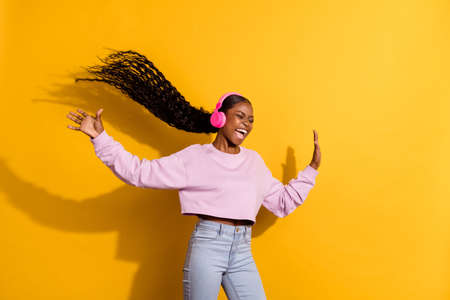 Photo of overjoyed carefree girl listen song mp3 raise hands scream isolated on yellow color backgroundの写真素材