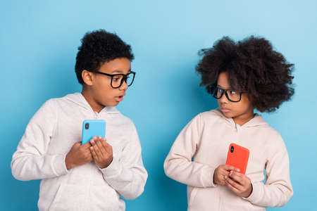 Portrait of small little trendy pre-teen friends using device hiding play game app smm isolated over...