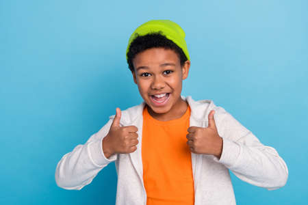 Portrait of handsome trendy funky cheerful boy schoolkid showing thumbup isolated over bright blue color backgroundの写真素材