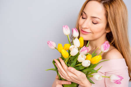 Cropped photo of charming lovely lady closed eyes smell fresh tulips isolated on grey color backgroundの写真素材