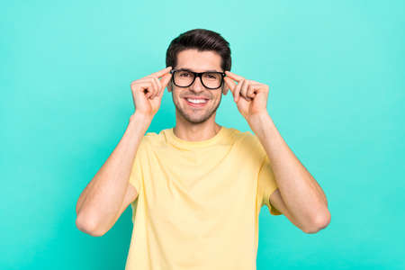 Photo of optimistic brunet guy wear eyewear yellow t-shirt isolated on turquoise color backgroundの写真素材