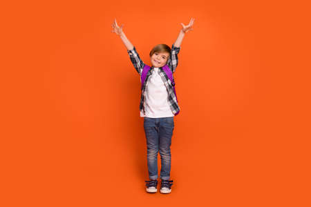Full length photo of young cheerful boy good mood hold arms up isolated over orange color backgroundの写真素材