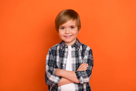 Photo of young cheerful little boy crossed hands wear casual clothes isolated over orange color backgroundの写真素材
