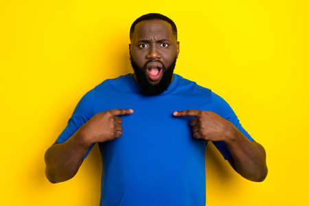Portrait of attractive mad worried guy pointing at himself ask why me isolated over bright yellow color backgroundの写真素材